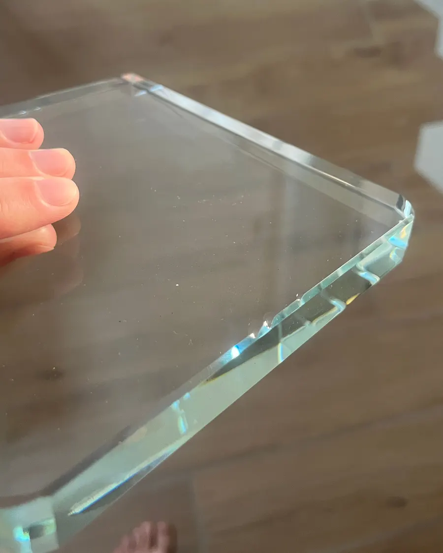 Cristal K9 brut tenu à la main, arêtes biseautées aux reflets vert d’eau